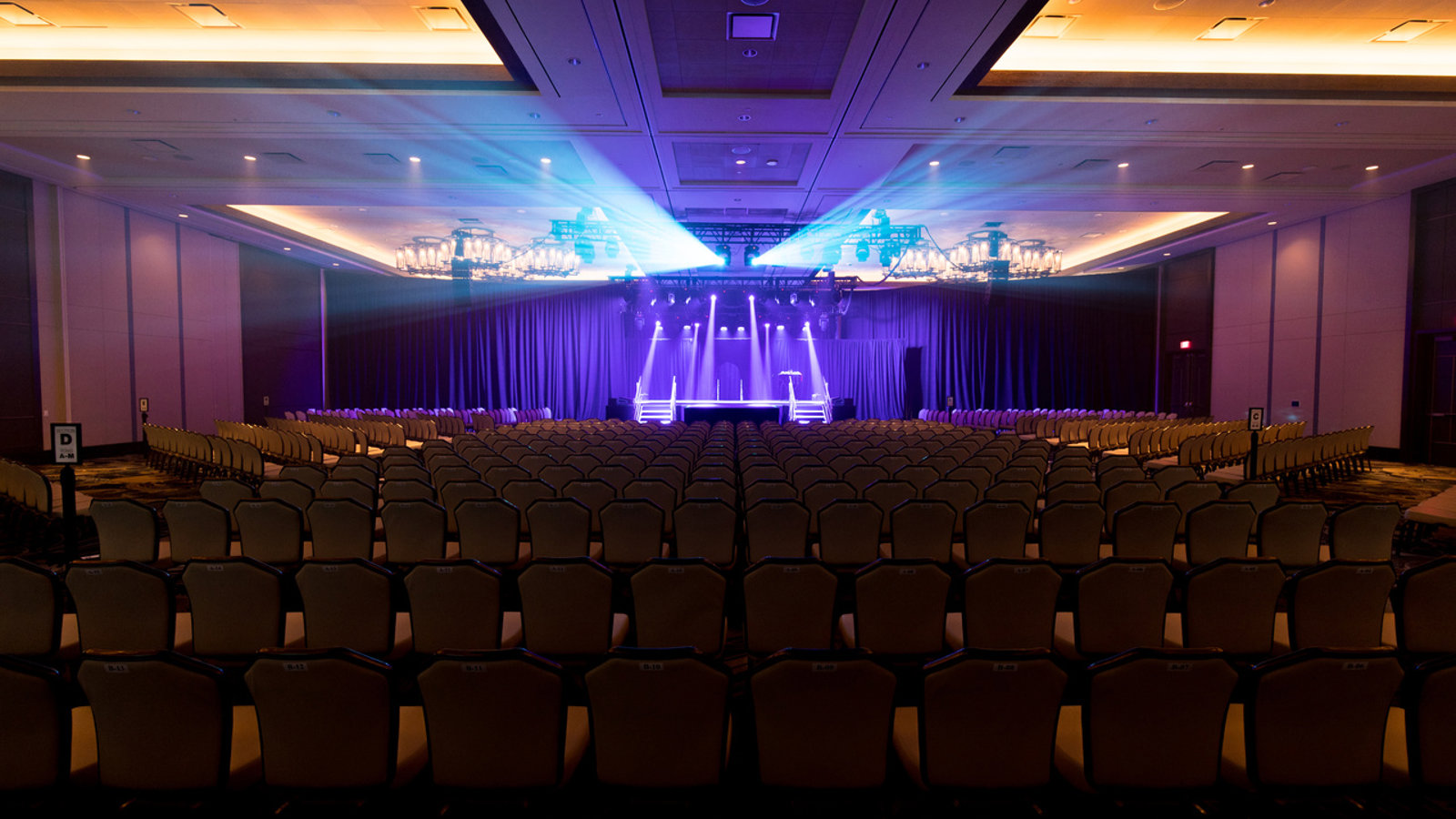 a large auditorium with rows of chairs and stage lights