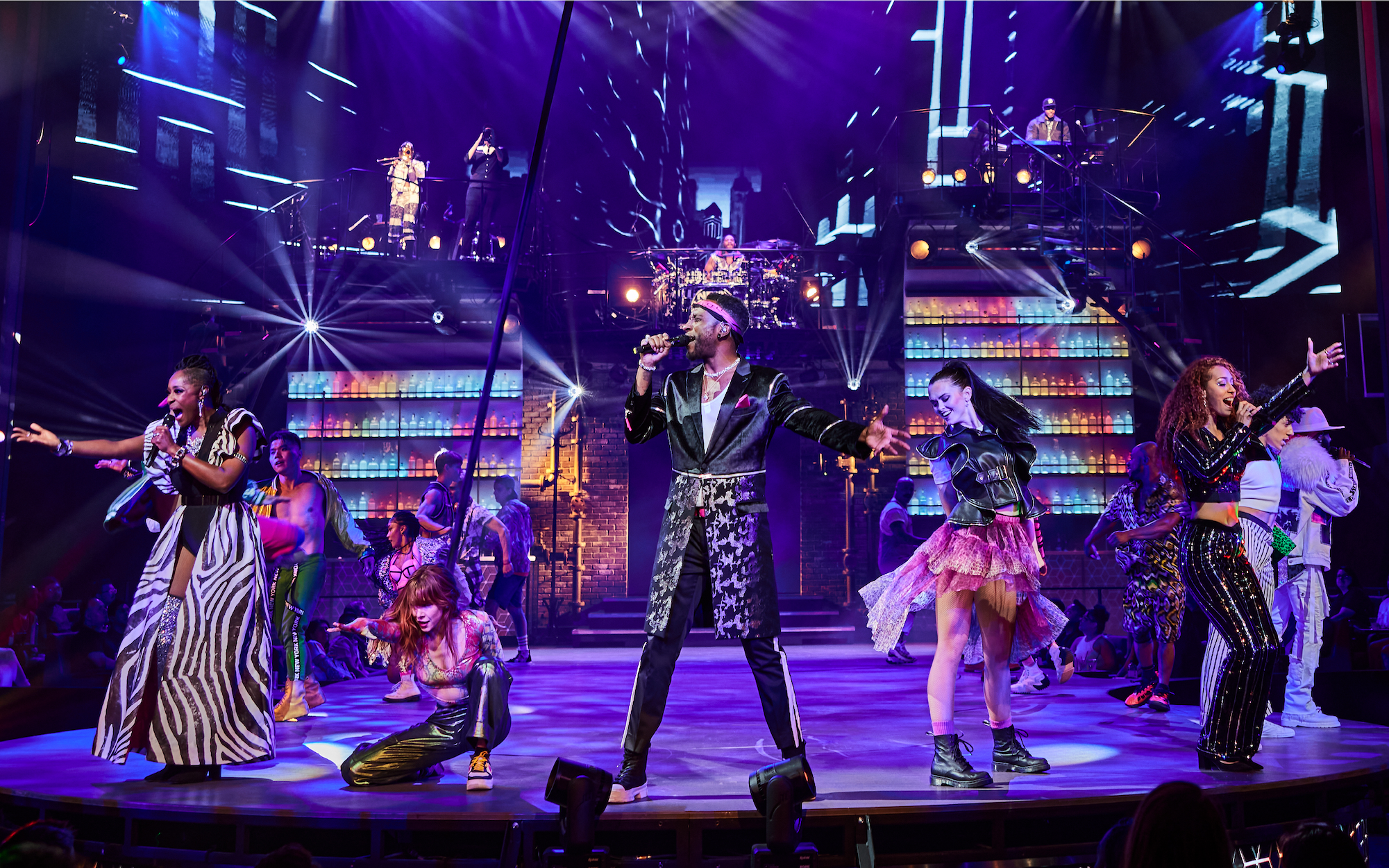 a person singing on a stage with people in the background
