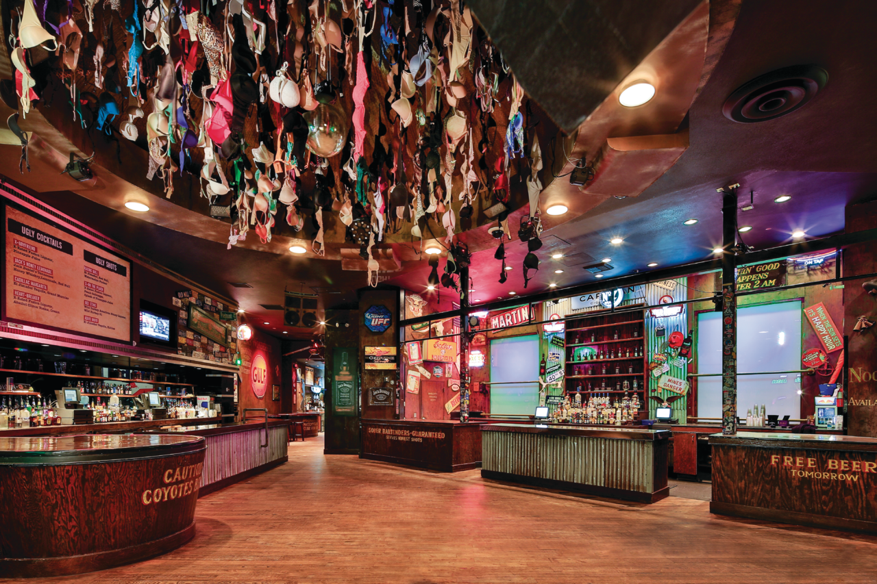 a room with a bar and counter with a variety of garments from the ceiling