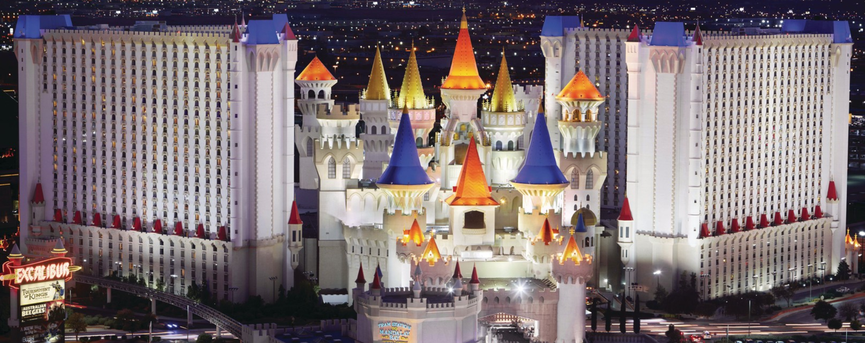 a large white castle with colorful towers with Excalibur Hotel and Casino in the background