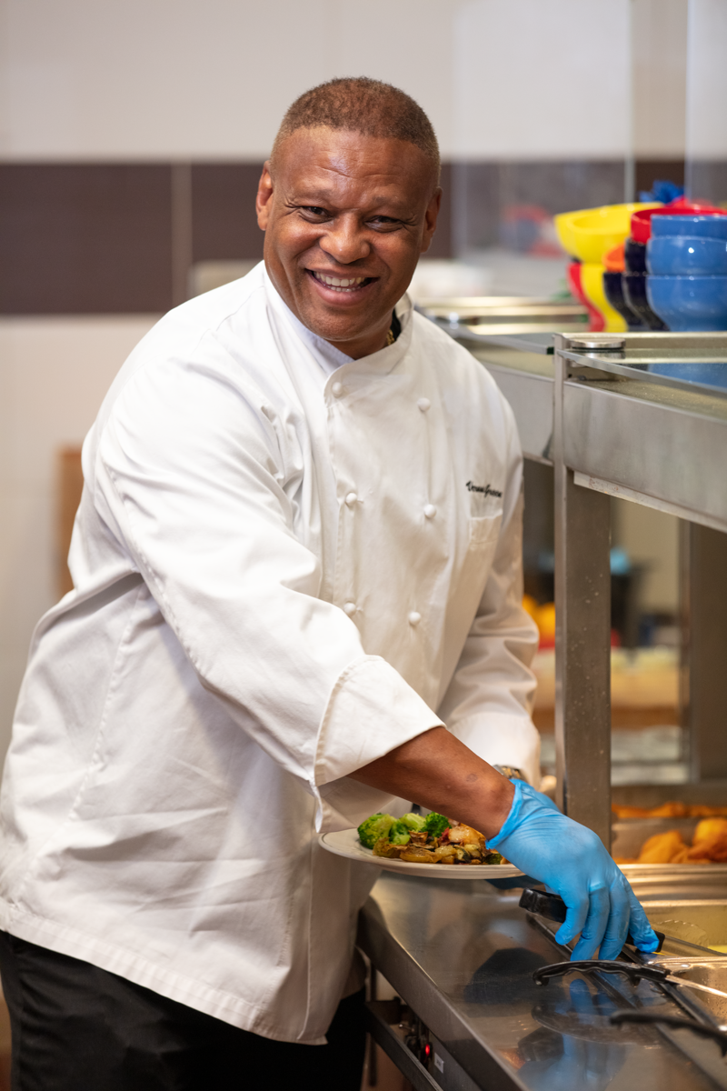 a person wearing a white coat and gloves holding a plate of food
