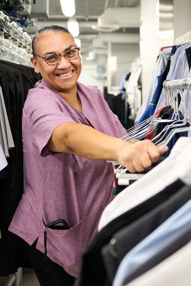 a person smiling at a rack of clothes
