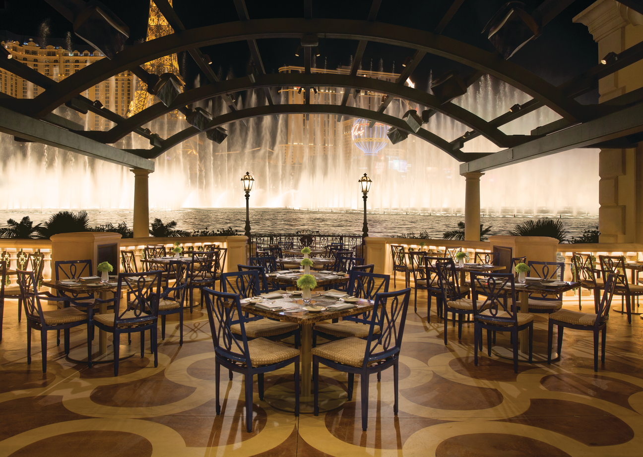 a restaurant with tables and chairs and a fountain in the background