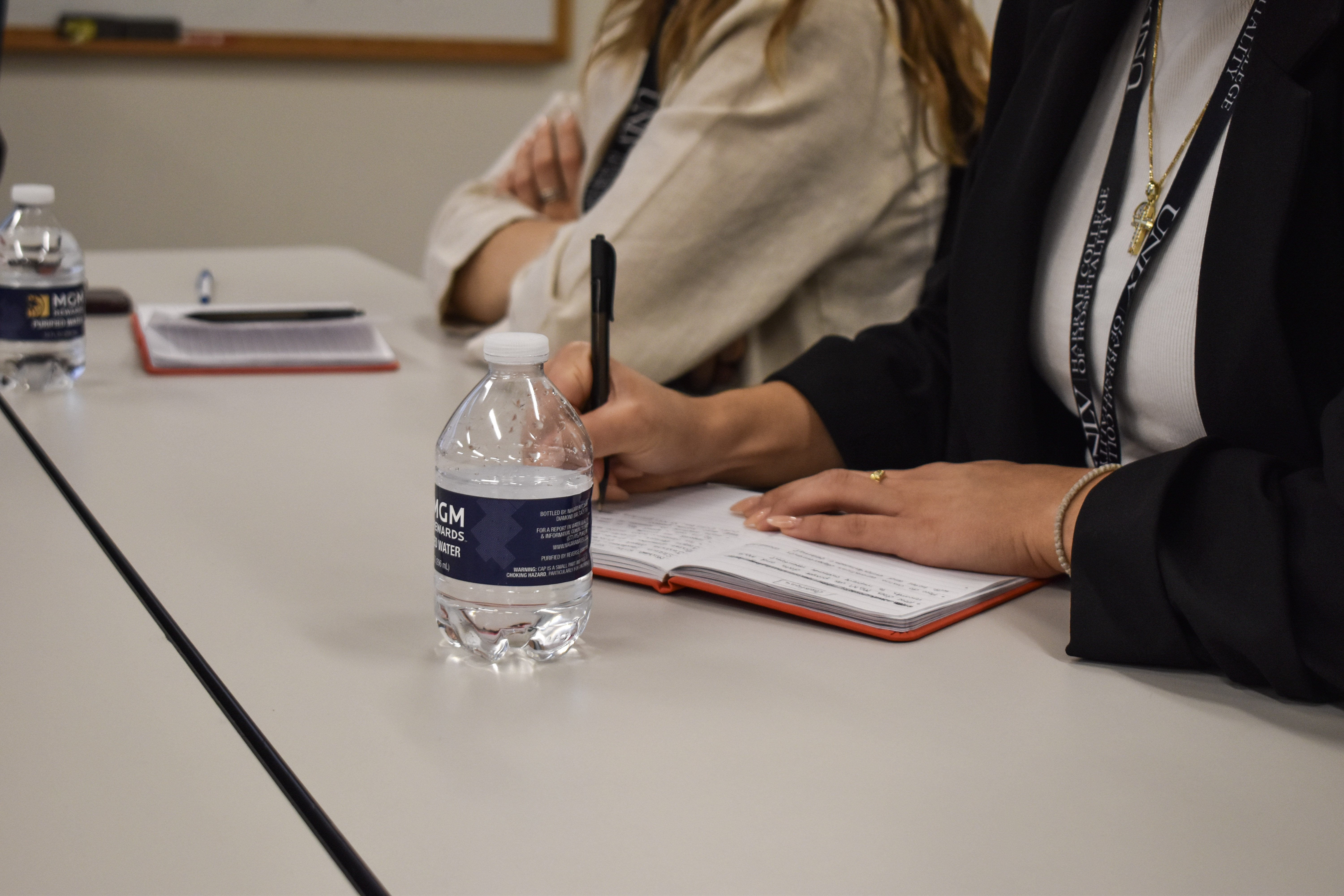 a person holding a pen and a notebook on a table