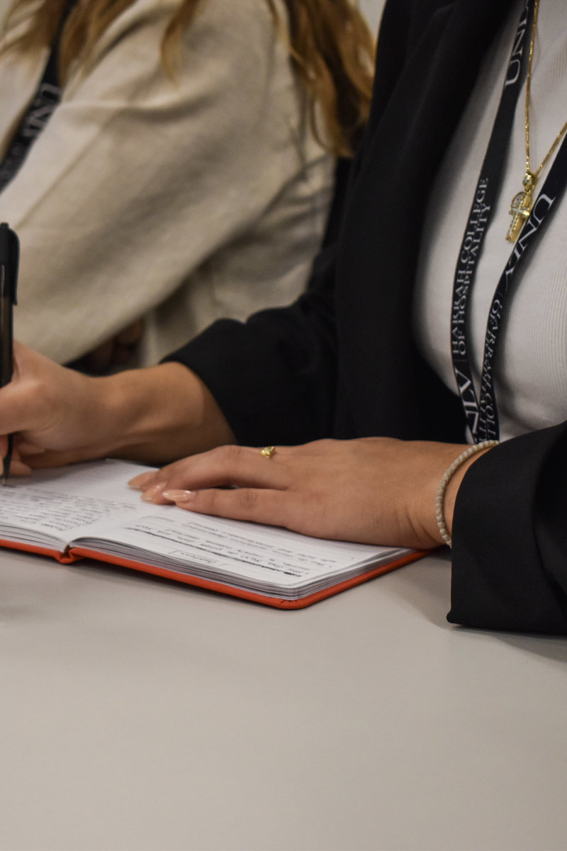 a person holding a pen and a notebook on a table