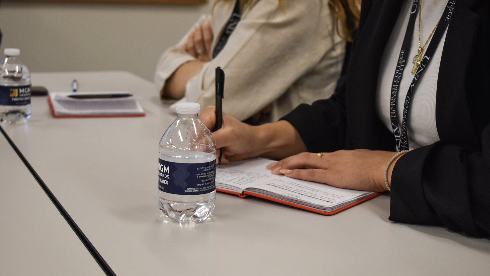 a person holding a pen and a notebook on a table
