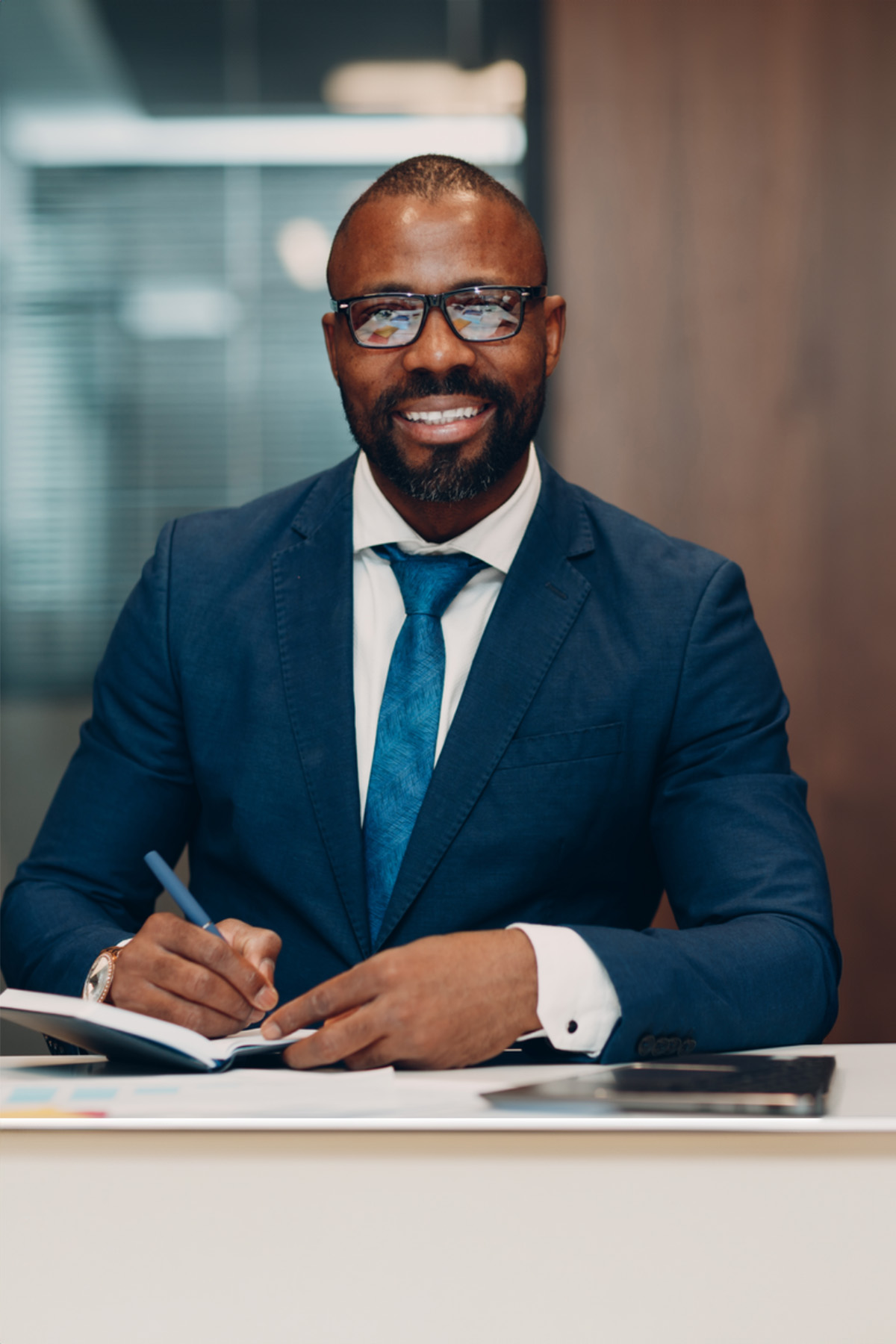 a person in a suit and tie writing on a notebook
