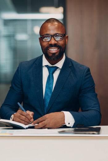 a person in a suit and tie writing on a notebook