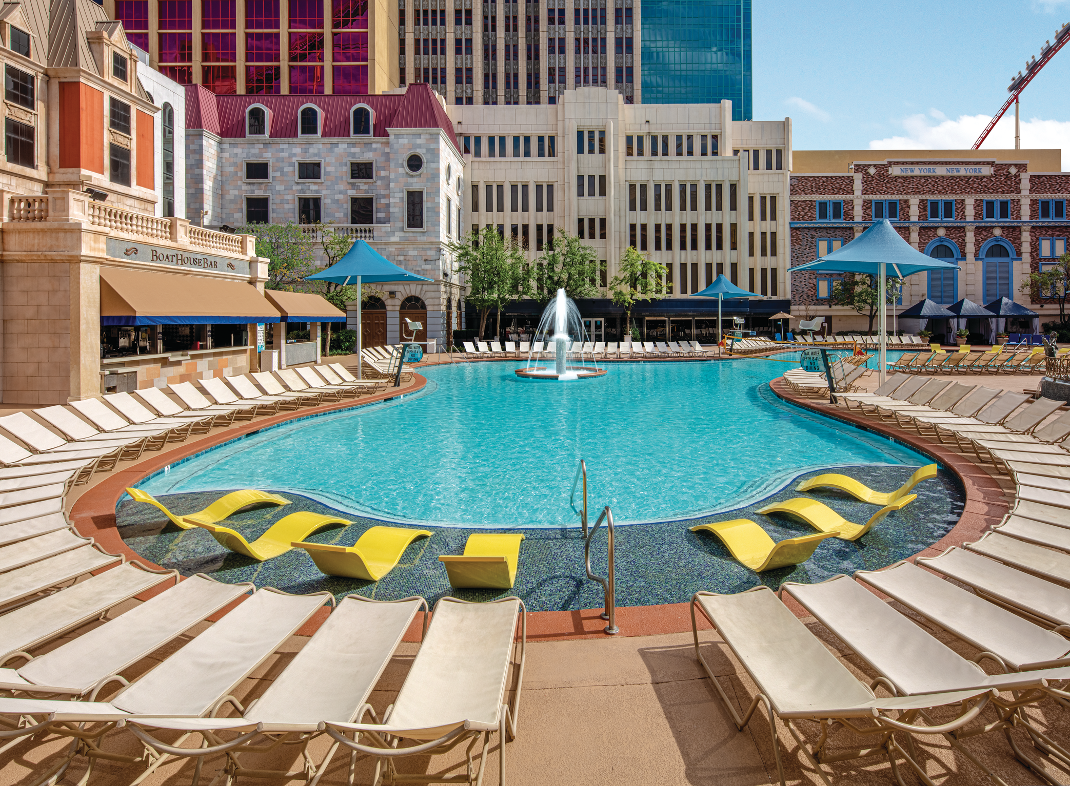 a pool with chairs and a fountain in the background