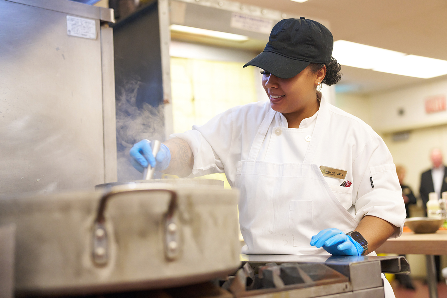a person wearing a hat and gloves cooking in a kitchen