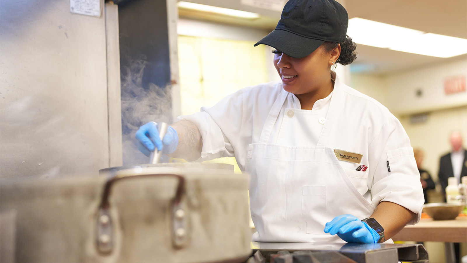 a person wearing a hat and gloves cooking in a kitchen