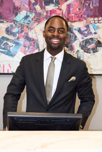 a person in a suit standing behind a computer