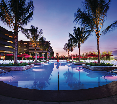 a pool with palm trees and umbrellas