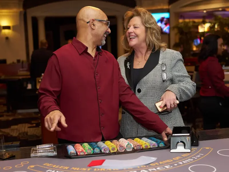 a person and person standing at a table with poker chips