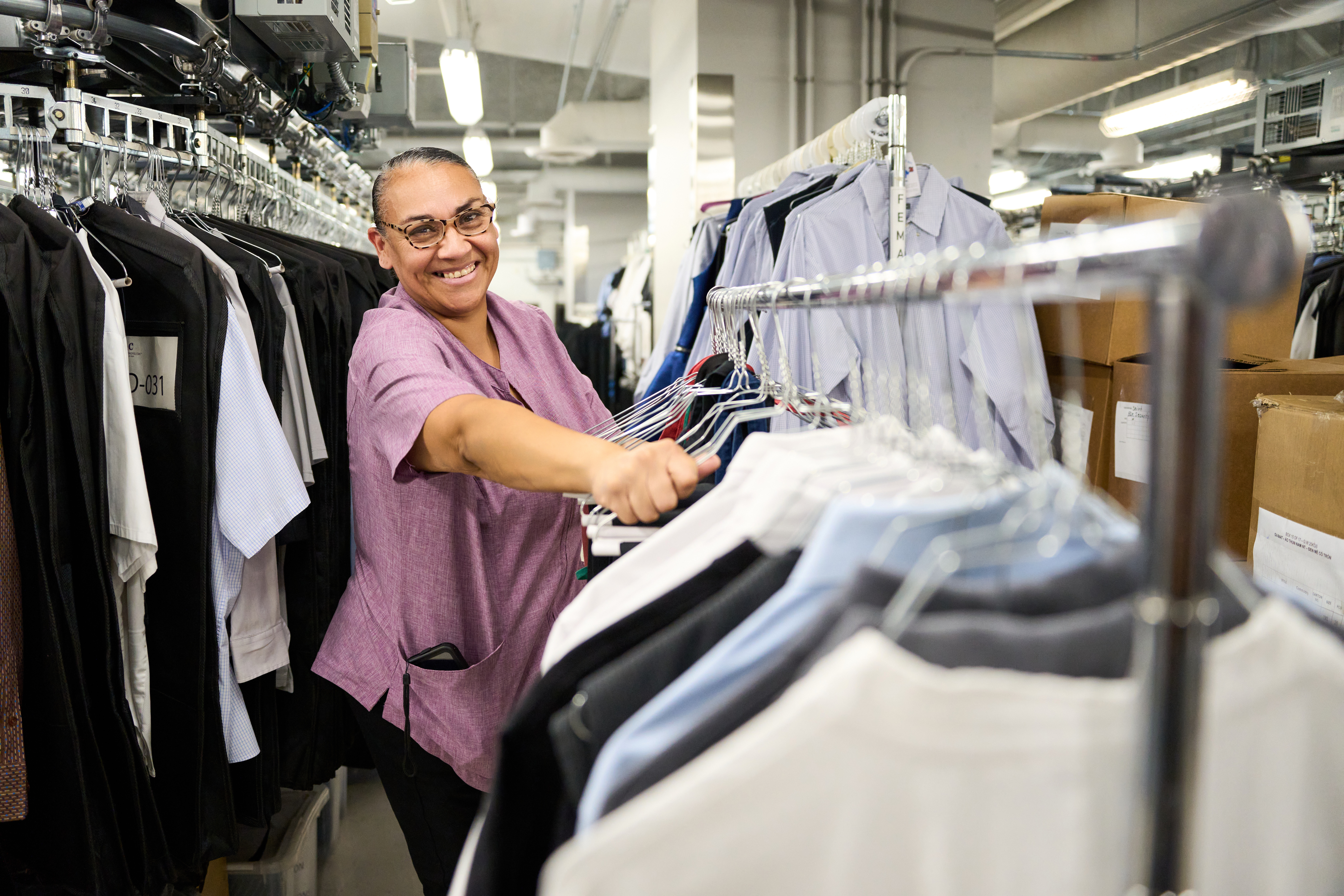 a person smiling at a rack of clothes