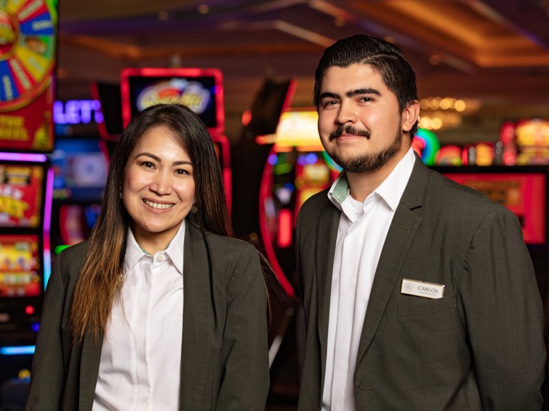 a person and person standing in front of slot machines