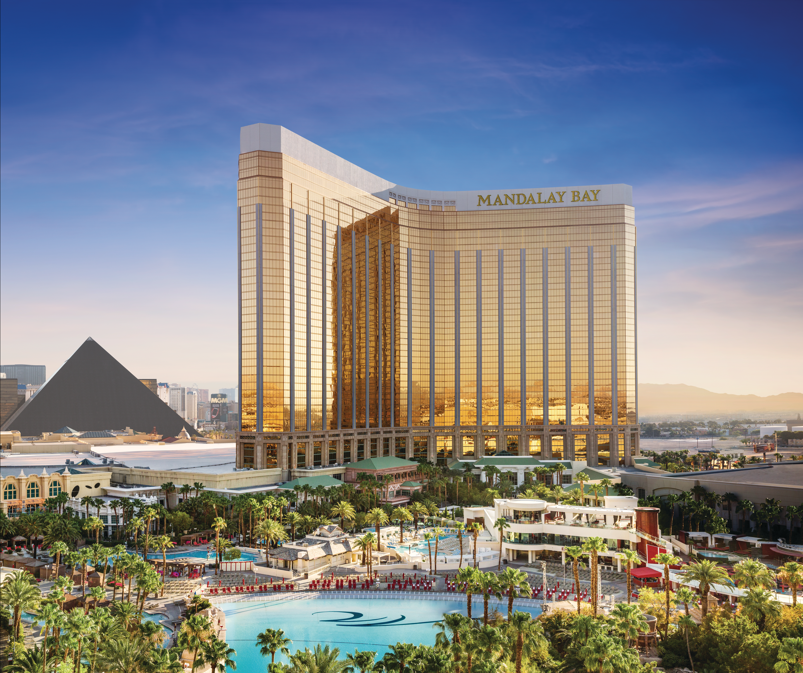 a large building with a pool in front of it with Mandalay Bay in the background