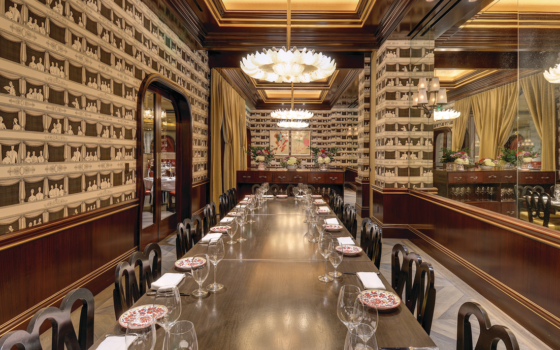 a long table with wine glasses and plates in a room with a chandelier