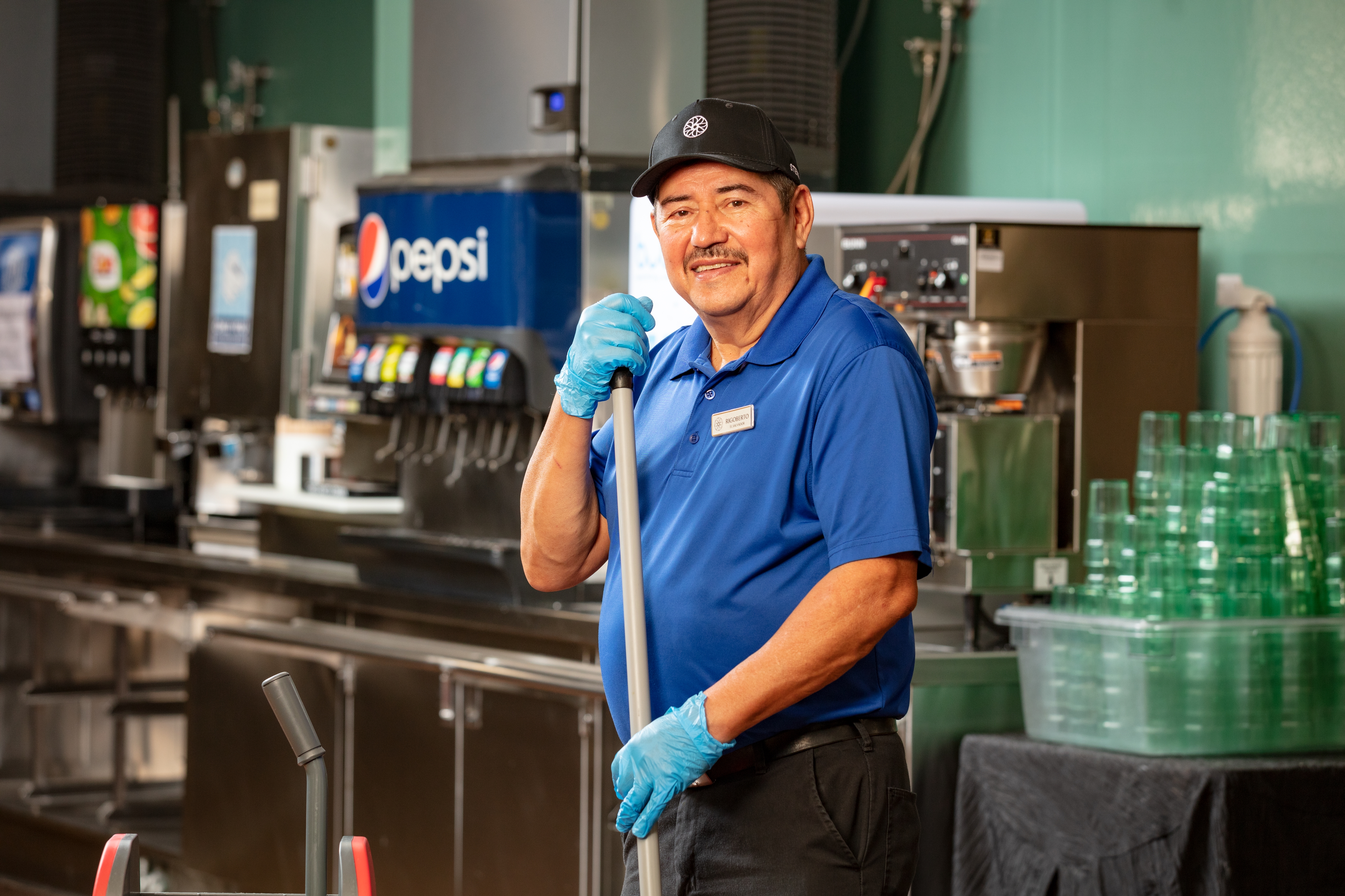 a person in a blue shirt and gloves holding a mop