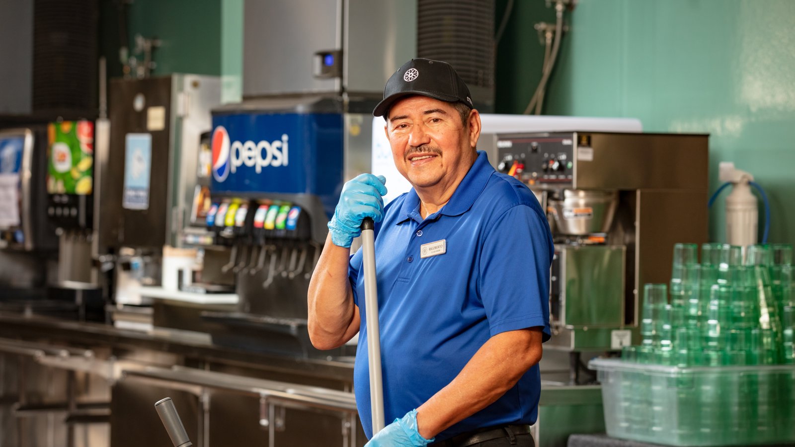 a person in a blue shirt and gloves holding a mop