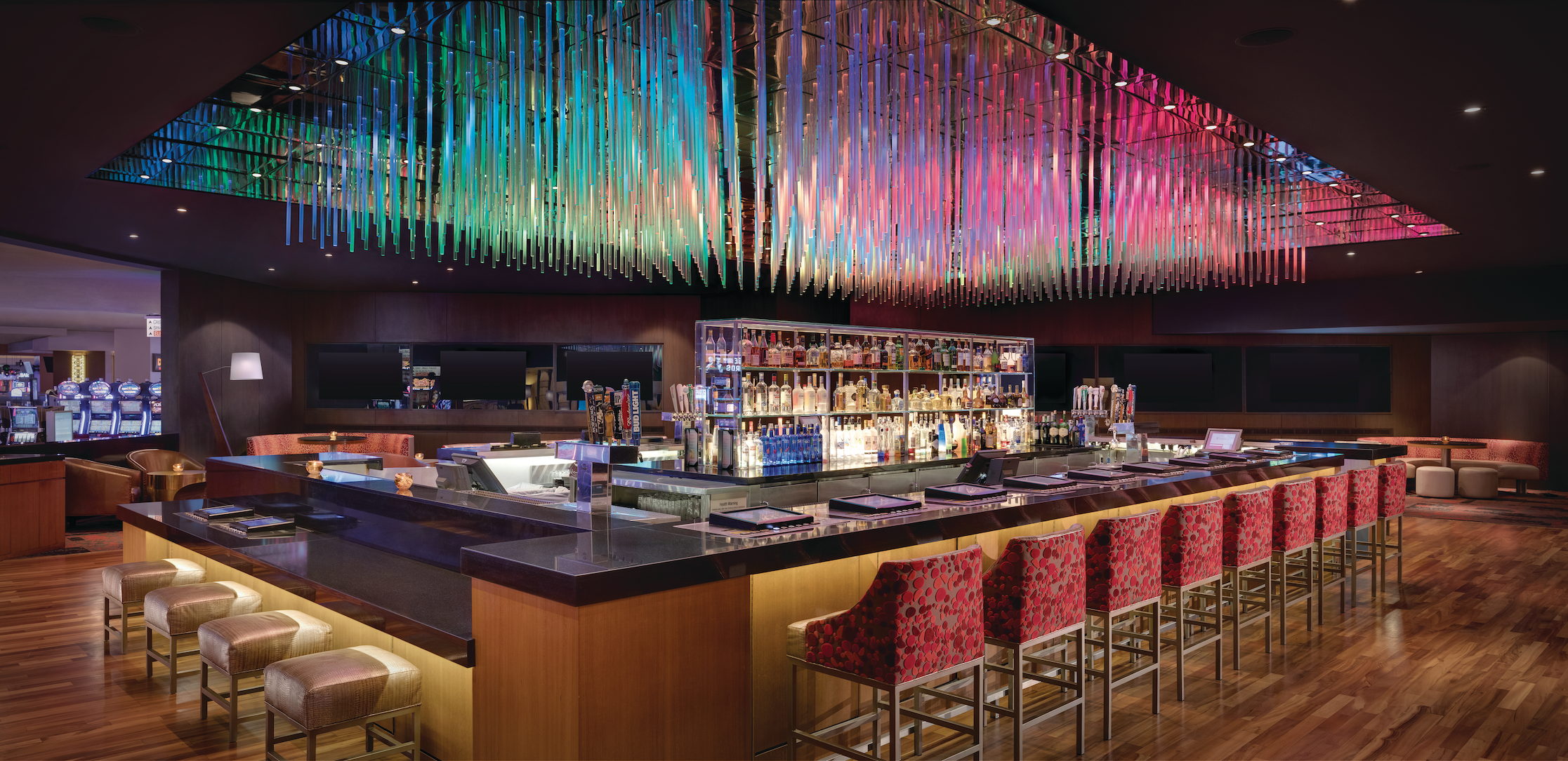 a bar with colorful lights from the ceiling